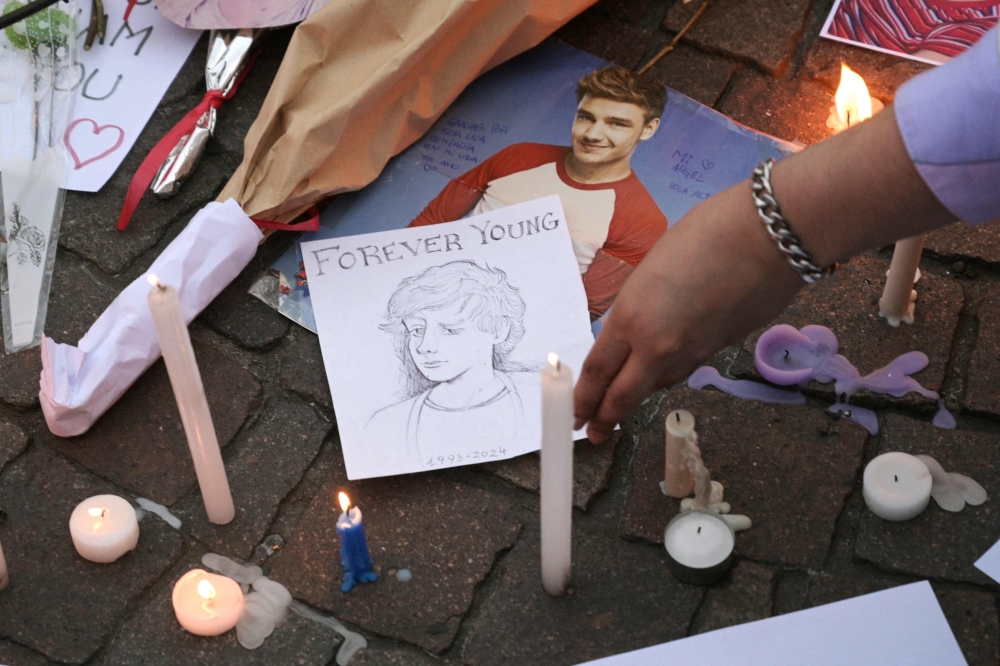 A fan places a handdrawn portrait of the late British singer Liam Payne at the Obelisco in Buenos Aires. — AFP