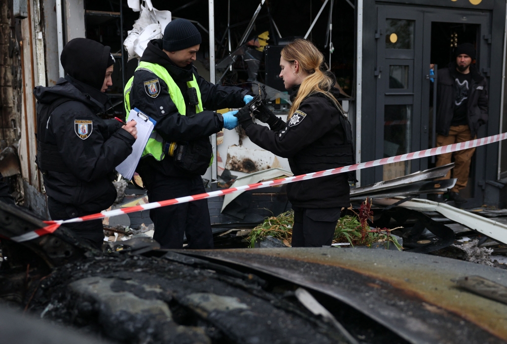 Police officers collect evidence at the site of a Russian drone strike in Kyiv on October 29, 2024. Malaysia’s IGP Tan Sri Razarudin Husain are checking claims that a Malaysian IC and driving licence were found in the European country’s Levadne area recently. — AFP pic