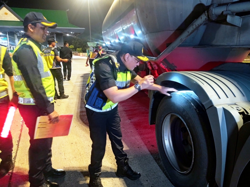 Kedah JPJ director Stien Van Lutam (right) inspects a lorry tyre during a commercial vehicles operation at the Hutan Kampung toll plaza in Alor Setar, Kedah on October 29, 2024. — Bernama pic