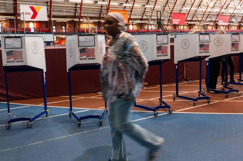 A poll worker walks by voting booths as New Yorkers participate in early voting at a polling site in Brooklyn on October 29, 2024 in New York City. — AFP pic