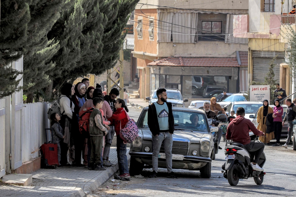 People wait along the side of a road for their ride before evacuating Lebanon's eastern city of Baalbek in the Bekaa Valley on October 30, 2024, after a statement from the Israeli army spokesperson warning residents of incoming strikes. — AFP pic