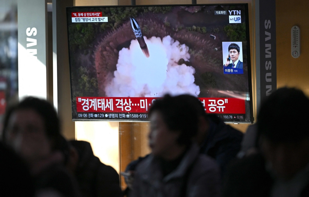 People watch a television screen showing a news broadcast with file footage of a North Korean missile test, at a train station in Seoul on October 31, 2024. — AFP pic