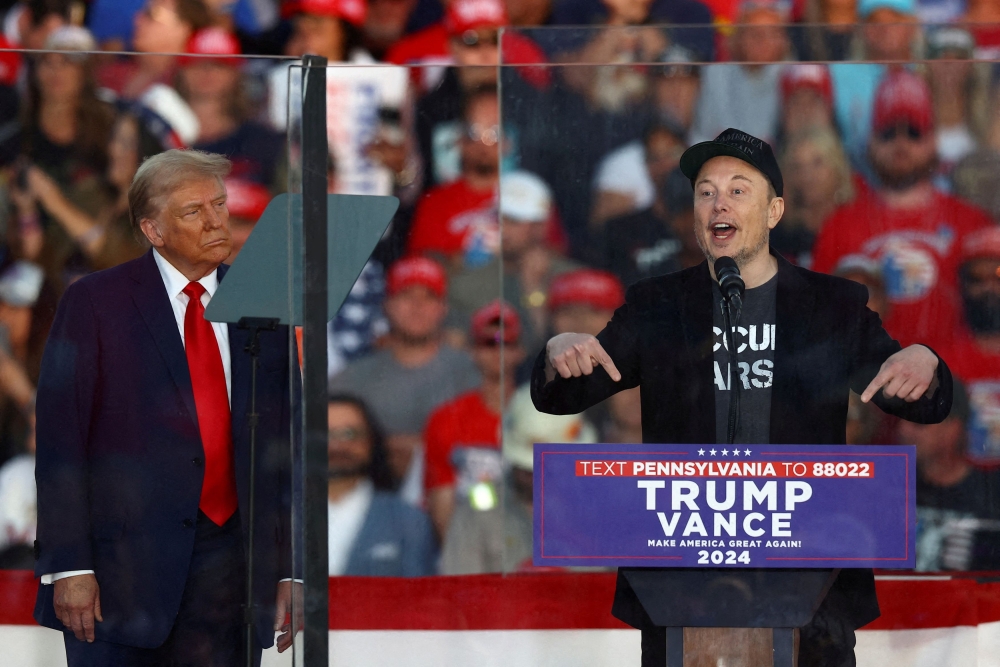 Tesla CEO and X owner Elon Musk speaks as Republican presidential nominee and former US president Donald Trump looks on during a rally at the site of the July assassination attempt against Trump, in Butler, Pennsylvania, October 5, 2024. — Reuters pic