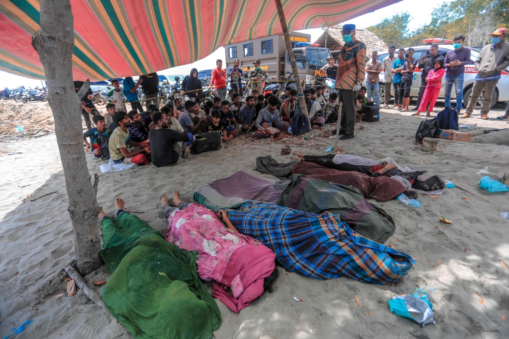 The bodies of Rohingya refugees are seen past surviving members of the persecuted minority, who were left stranded on the coast at Meunasah Asan village, in East Aceh, Aceh Province, October 31, 2024. — AFP pic