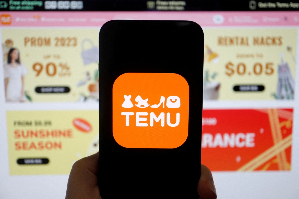 The logo of Temu is seen on a mobile phone displayed in front of its website, in this illustration picture taken April 26, 2023. — Reuters pic  