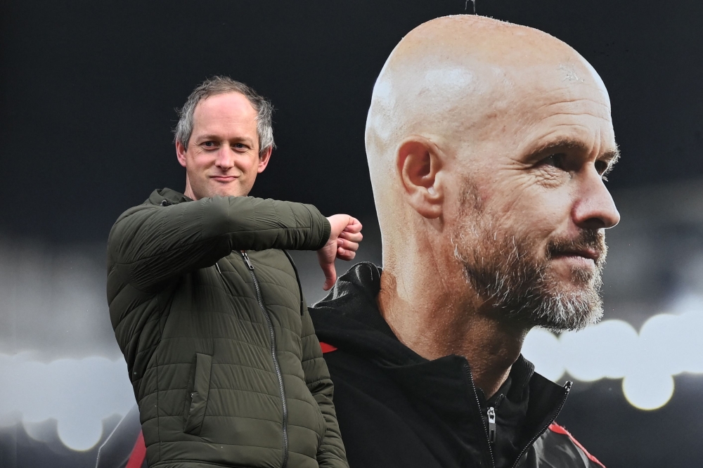 A visitor reacts as he poses in front of a picture of former Manchester United’s Dutch manager Erik ten Hag, outside Old Trafford — AFP pic