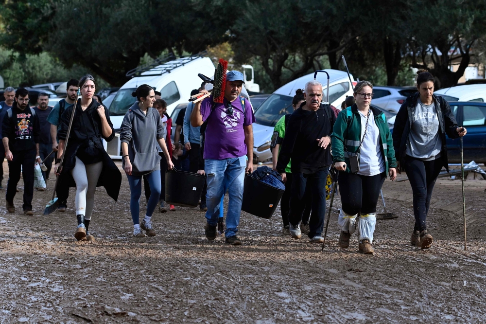 People walk along a muddy street on November 1, 2024, following the devastating effects of flooding in the town of Alfafar, in the region of Valencia, eastern Spain. — AFP pic