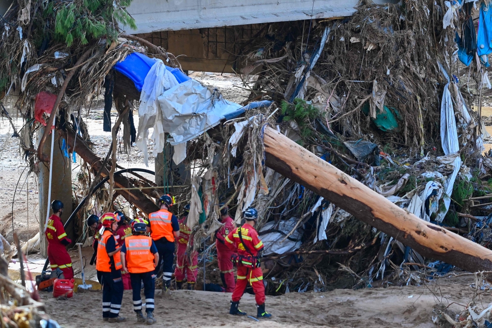 Rescuers search for victims along a river in the town of Paiporta. — AFP pic