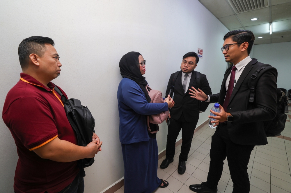 Fauziah Nordin (second from left) and Mujahid Nordin (left) listen to lawyers after the decision on the attack that left their sister in a coma was postponed at the Sessions Court in Johor Baru, on Nov 3, 2024. — Bernama pic
