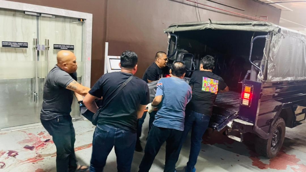 Police personnel move the victim’s body into a vehicle. — Photo courtesy of Bintulu police