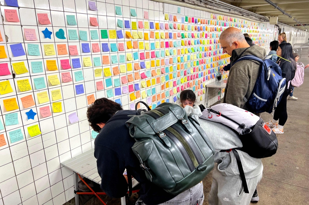 People leave post-it notes as they take part of the Subway Therapy project are pictured at the 14th St/6th Ave station bypass in New York City on November 8. — AFP pic