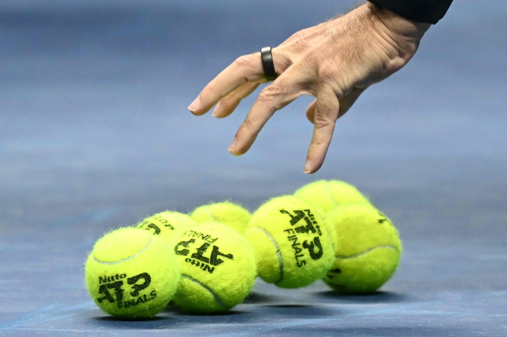 A person grabs official tennis balls during the ATP Finals tennis tournament in Turin on November 11, 2024. — AFP pic