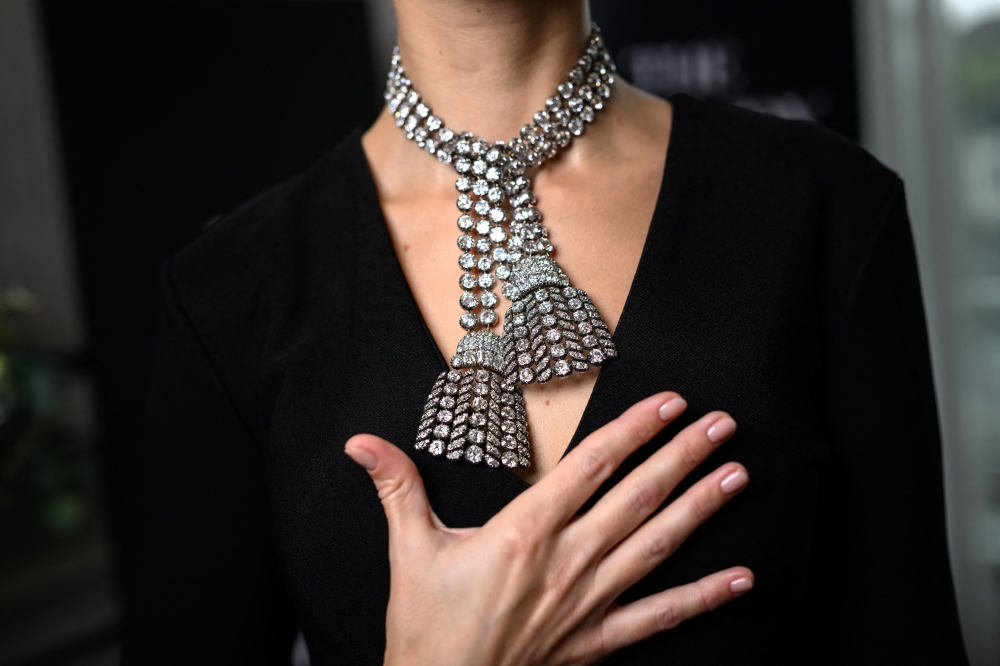 A woman wearing an 18th century diamond jewel necklace composed of three rows of diamonds finished with a diamond tassel at each, weighing approximately 300 carats, poses during a press preview at Sotheby’s auction house in Geneva, on November 7, 2024. — AFP pic