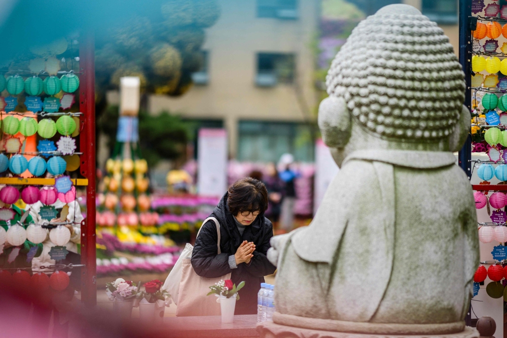 A woman prays at the Jogyesa Buddhist temple in Seoul as South Korean students sit for the yearly university entrance exam known locally as Suneung, on November 14, 2024. — AFP pic