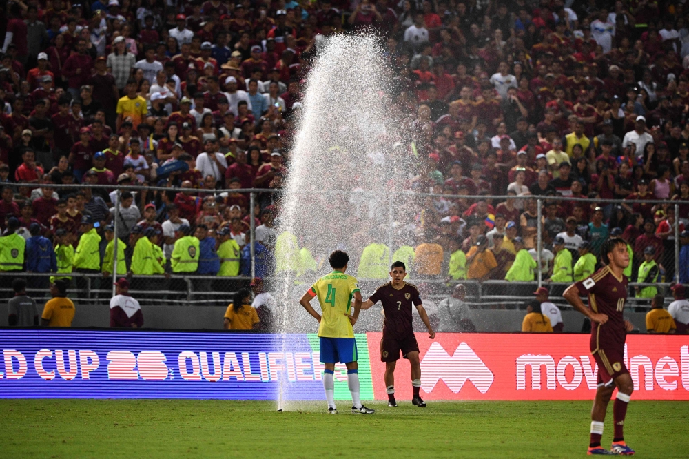 Brazil's defender Marquinhos and Venezuela's midfielder Jefferson Savarino stand next to a water sprinkler during the 2026 FIFA World Cup South American qualifiers football match between Venezuela and Brazil at the Monumental stadium in Maturin, Monagas State, Venezuela, on November 14, 2024. — AFP pic