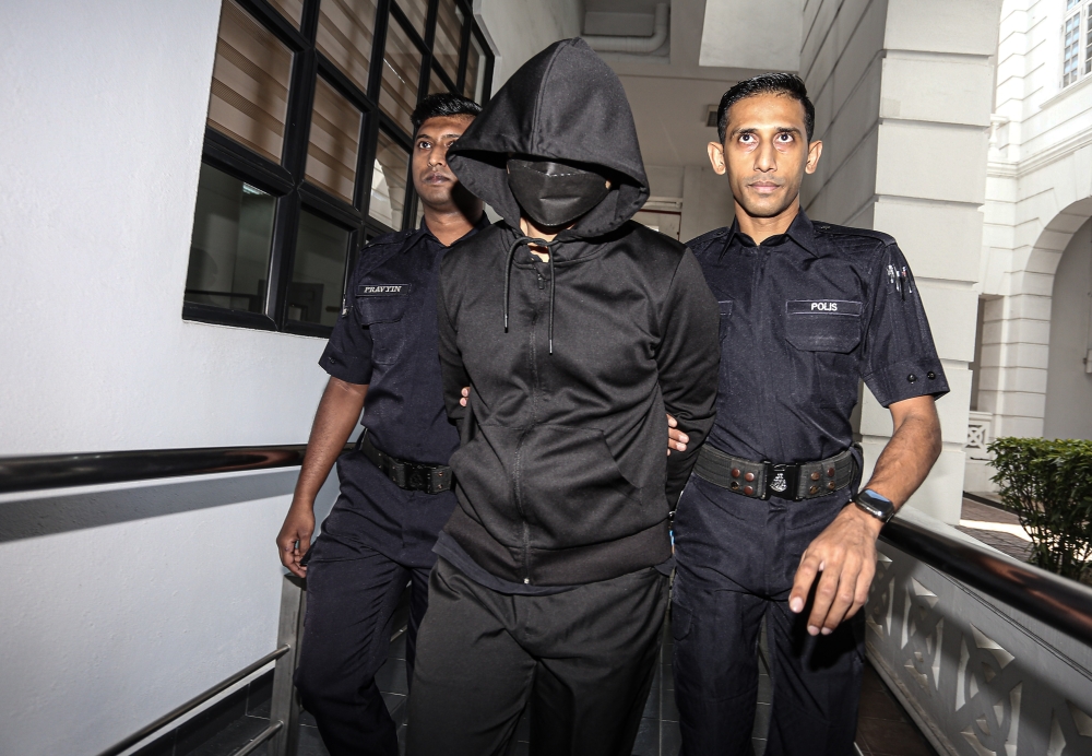 Senior police officer DSP Mohd Nazri Abdul Razak (in hood and mask) is brought to the High Court in Ipoh, on Nov 11, 2024. — Bernama pic