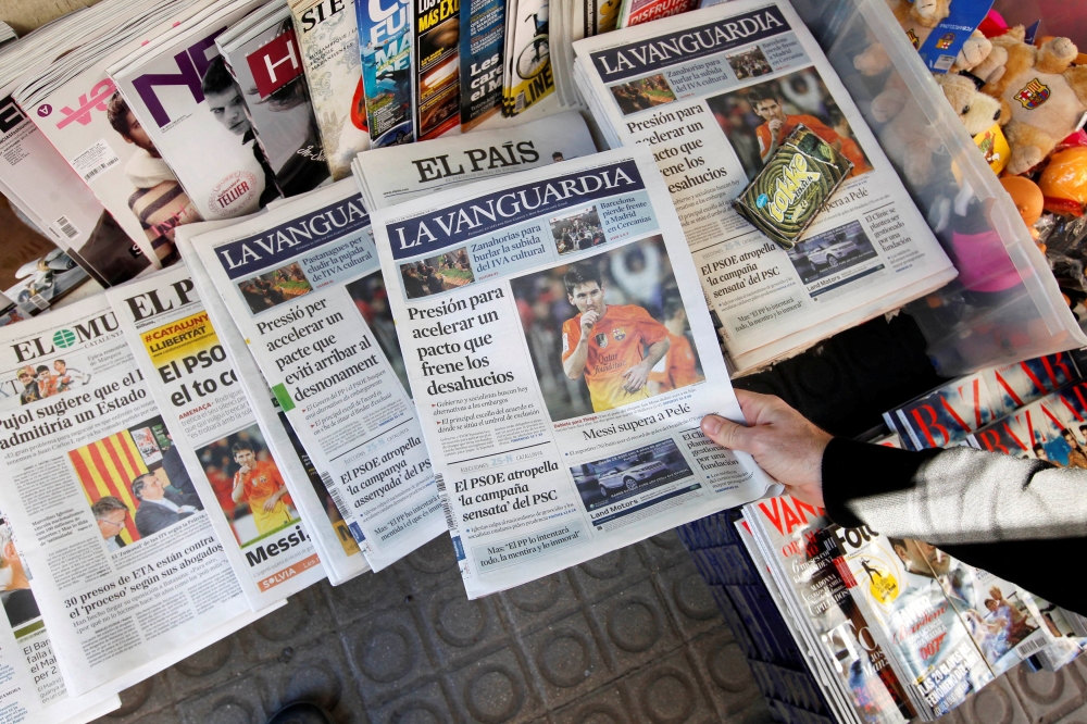 A person grabs a copy of the newspaper La Vanguardia written in Spanish placed next to a copy written in Catalan at Plaza de Catalunya in central Barcelona November 12, 2012. — Reuters pic