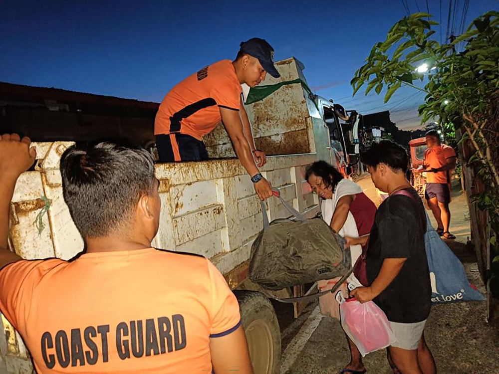 This handout photo taken on November 15, 2024 and released by the Philippine Coast Guard (PCG) on November 16 shows coast guard personnel evacuating residents during an operation in Virac town, Catanduanes province, ahead of the arrival of Typhoon Many-yi. Philippine authorities ordered all vessels back to shore and people in coastal communities to leave their homes on November 16 as Typhoon Man-yi neared the storm-weary archipelago nation, with forecasters expecting it to intensify before making landfall. — Philippine Coast Guard handout pic via AFP