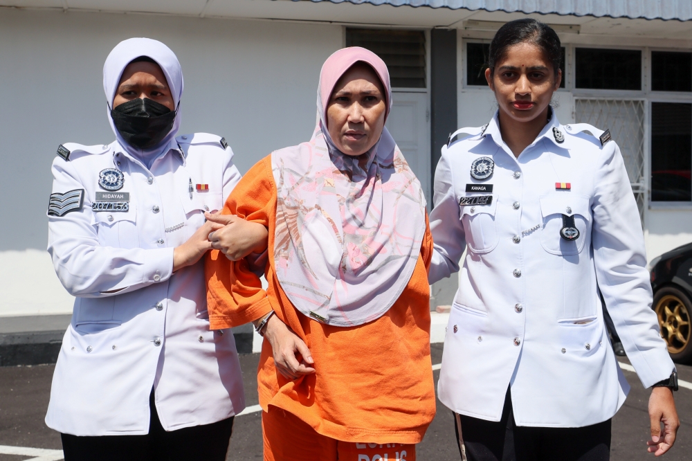Norizan Ismail (centre) is escorted to the Dungun magistrates court to be charged, on Oct 15, 2024. — Bernama pic
