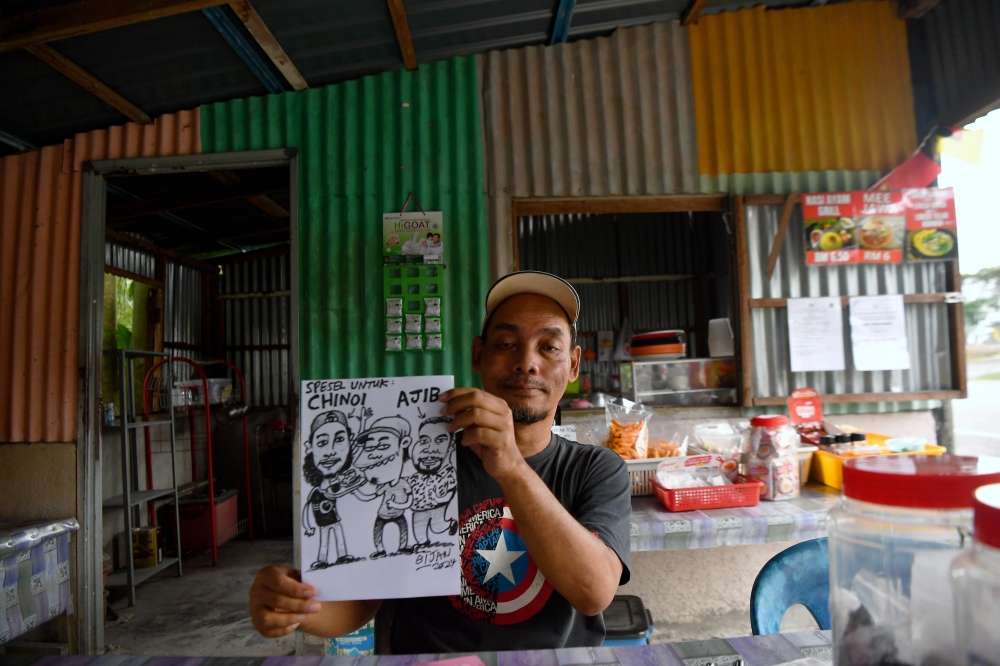 Cartoonist Syahru Maizam Jamin, 51, also known as Bijan, showcases his artwork during an interview with Bernama recently at his eatery in Malim Nawar, Kampar, Perak, November 18, 2024. — Bernama pic 