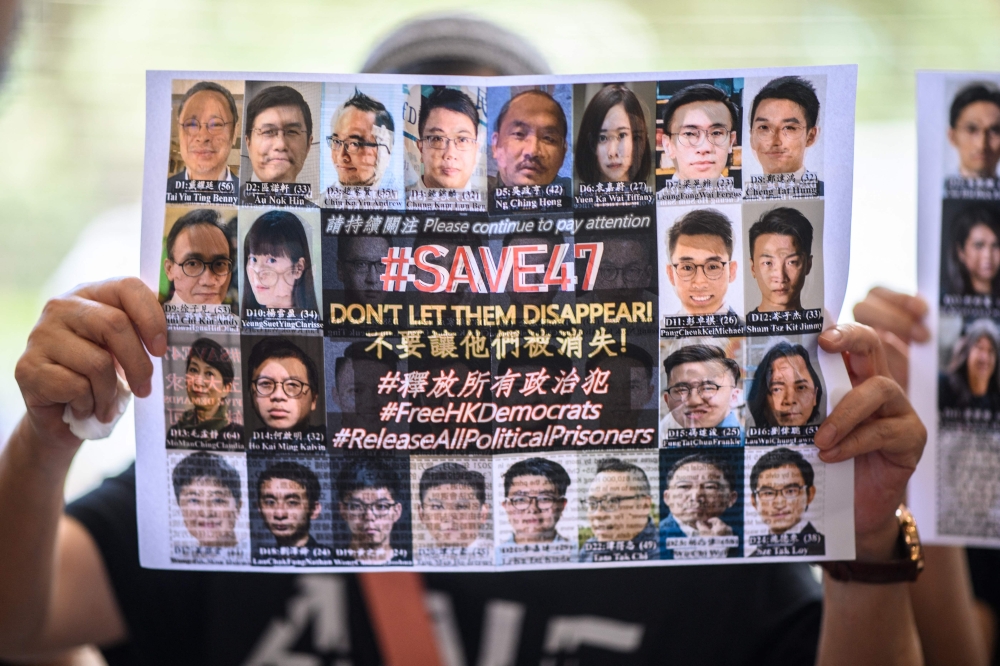 A supporter holds a poster showing some of the 47 pro-democracy activists on trial at the West Kowloon Court in Hong Kong on July 8, 2021, on charges of conspiracy to commit subversion under the national security law for taking part in unauthorised pro-democracy primaries in July 2020.  Hong Kong's largest national security trial will draw to a close today, with dozens of the city's most prominent democracy campaigners set to be sentenced for subversion, a charge which can carry up to life imprisonment. — AFP pic