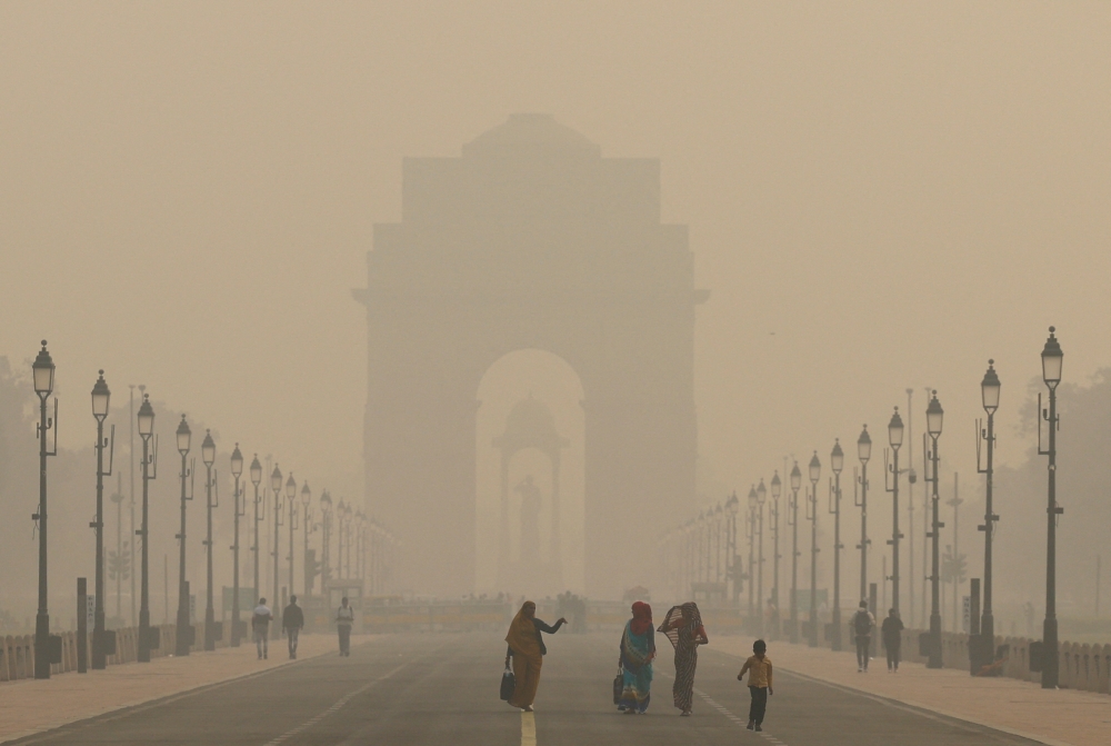 Women walk on a road near India Gate as the sky is enveloped with smog after Delhi's air quality worsened due to air pollution.— Reuters