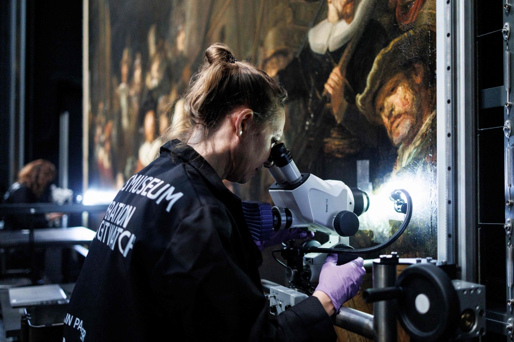 A technician works on the restoration of Rembrandt’s masterpiece ‘The Night Watch’ at the Rijksmuseum, in Amsterdam. — AFP pic