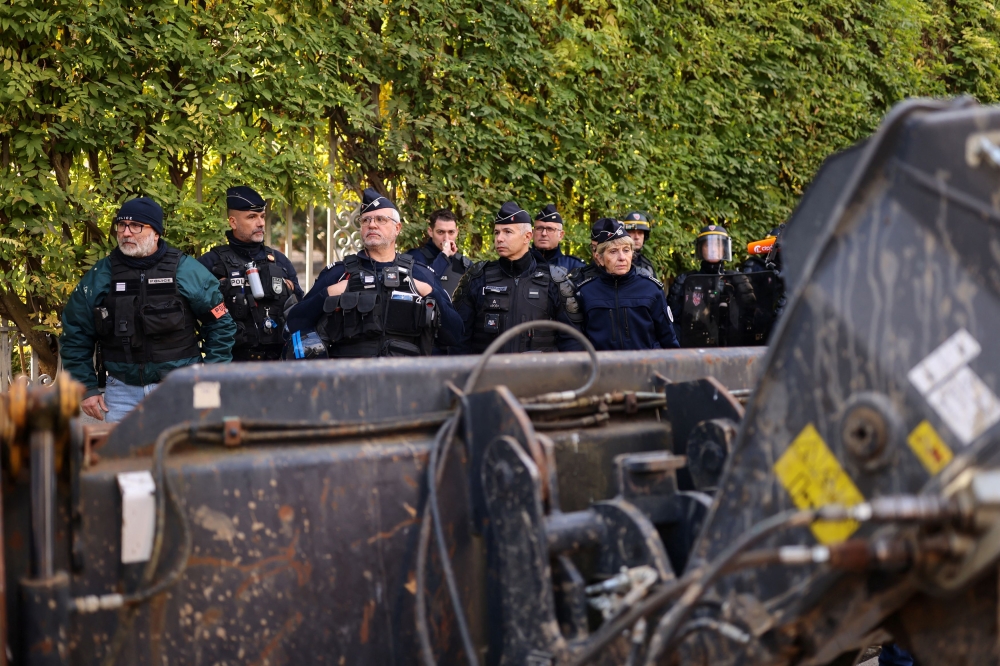 The blade of a French farmer’s tractor blocks the French police standing in position as French farmers gather with their tractors in front of the Lot et Garonne Prefecture to protest against the prospect of a trade agreement between the European Union (EU) and the Latin American countries united within Mercosur, and to demand more social aid amid rain-hit harvests and disease outbreaks, in Agen, France, November 19, 2024. — Reuters pic