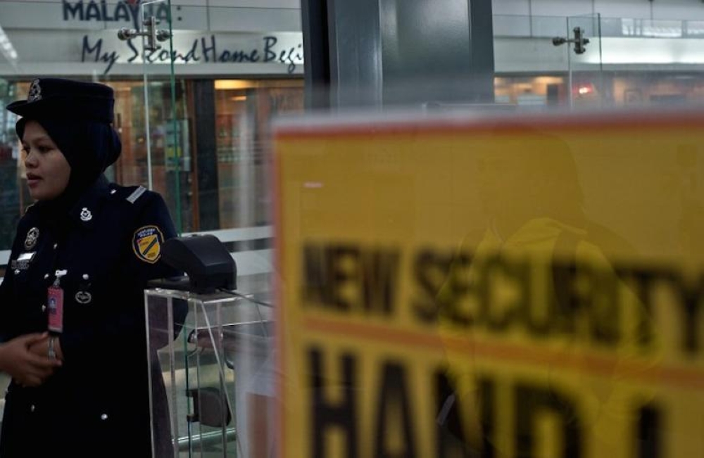 A police officer stands guard next to security regulation signage at the departure hall of the Kuala Lumpur International Airport in Sepang on March 10, 2014. — AFP pic