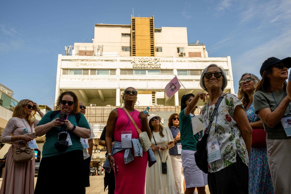 In this photo taken on September 25, 2024, members of a K-drama tour group gather outside the Sewoon Shopping Center in Seoul, which was used as a filming location for the K-drama crime thriller series 'Vincenzo'. — AFP pic