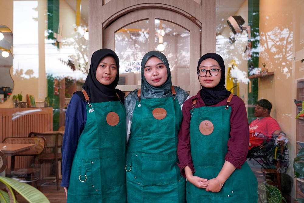 Morning Mama owner Qurrata Ayuni (C), who lost her parents in the 2004 tsunami, poses alongside staff members at her cafe in Banda Aceh. — AFP pic