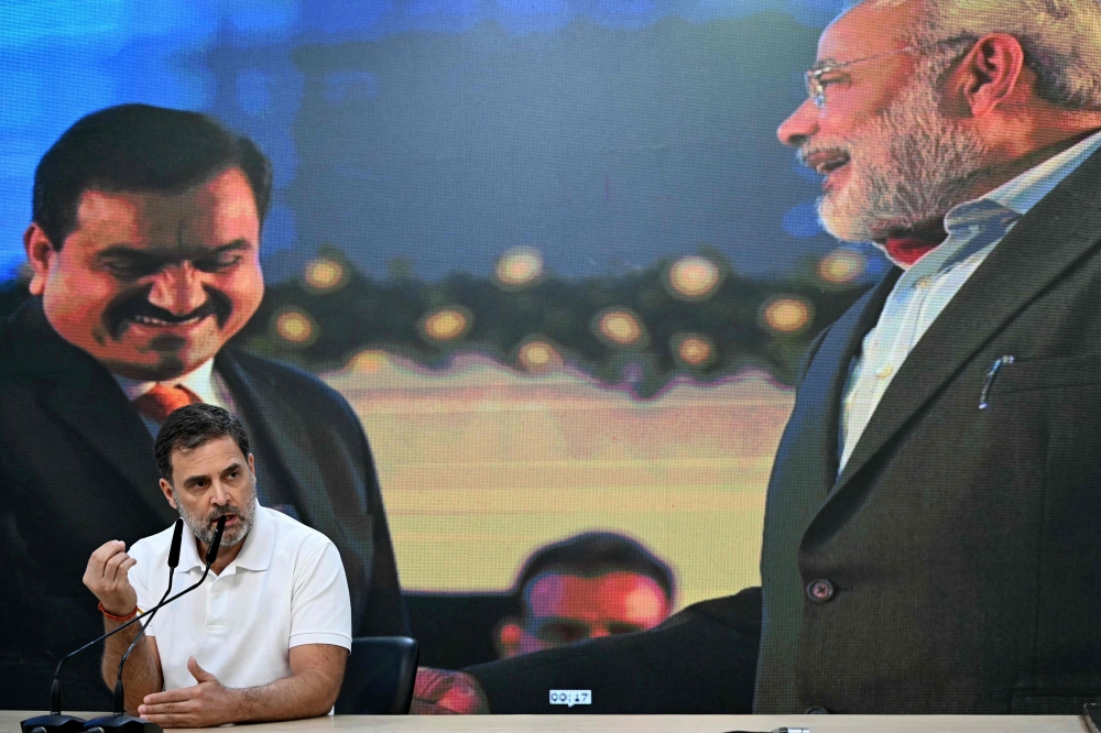 India’s Congress party leader Rahul Gandhi (centre) addresses a press conference against a backdrop of pictures of Indian industrialist Gautam Adani (left) and India’s Prime Minister Narendra Modi, at his party headquarters in New Delhi on November 21, 2024. — AFP pic