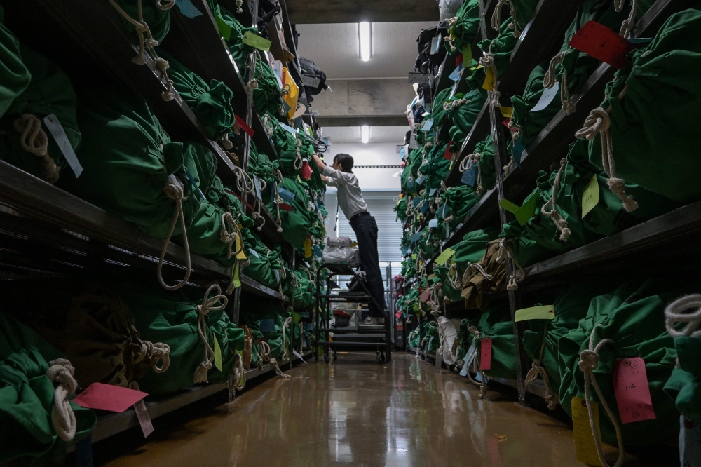 An employee works on thousands of items — all bagged, tagged and organised based on where and when they were lost — at the Tokyo Metropolitan Police Department Lost and Found Centre in the Iidabashi area of central Tokyo August 2, 2024. — AFP pic