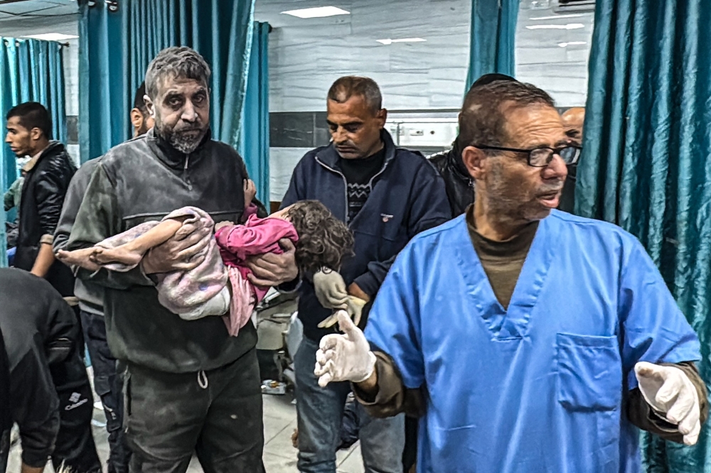 A Palestinian man carries a young child inside the Kamal Adwan hospital following an Israeli strike that hit an area near the medical establishment in Beit Layia in the northern Gaza Strip early on November 21, 2024. — AFP pic