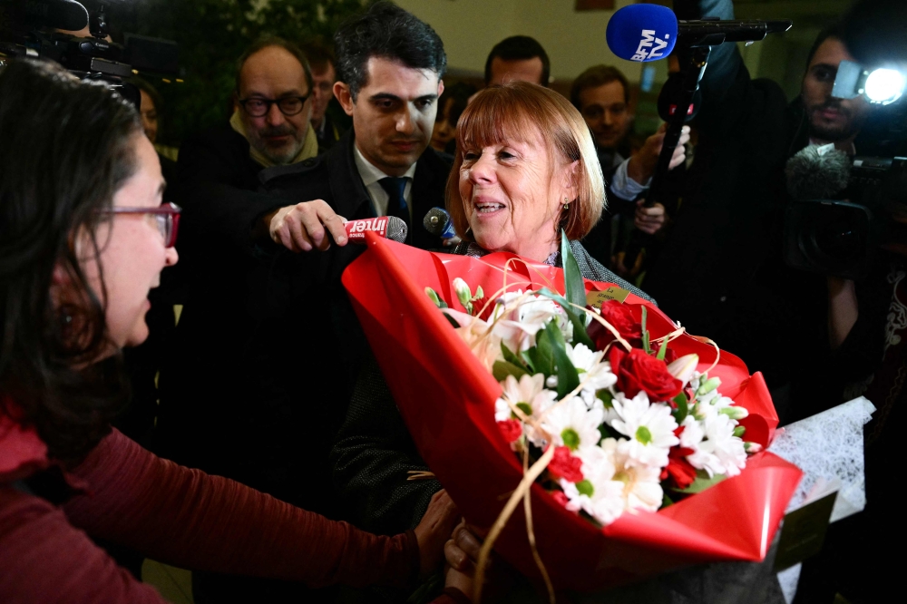 Gisele Pelicot flanked by her lawyer Stephane Babonneau (centre) speaks with a supporter as she leaves the Avignon courthouse after attending the trial of her former partner Dominique Pelicot accused of drugging her for nearly 10 years and inviting strangers to rape her at their home in Mazan, in Avignon, southern France, November 25, 2024. — AFP pic