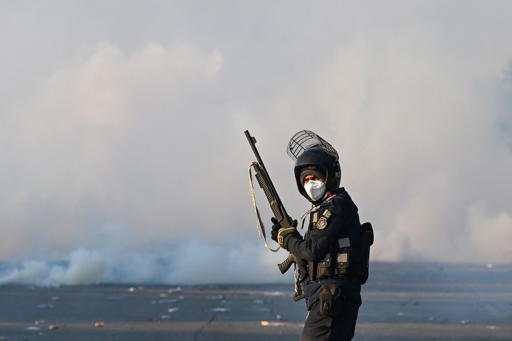 A policeman stands amid tear gas as supporters of Pakistan Tehreek-e-Insaf (PTI) party protest to demand the release of former prime minister Imran Khan, in Islamabad on November 26, 2024. Thousands of protestors calling for the release of Pakistan's jailed ex-prime minister Imran Khan defied roadblocks and tear gas to march to the gates of the nation's capital today. — AFP pic