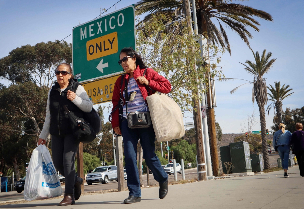 Shoppers walk with their purchases near the US-Mexico border in San Ysidro, California, on November 26, 2024. US President-elect Donald Trump threatened to begin his presidency with a massive trade war –– and diplomatic crisis –– as he demanded China, Canada and Mexico stop illegal immigration and drug smuggling into the United States or face punitive US import tariffs. –– AFP pic