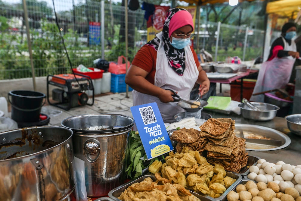 A vendor displays a standee with a QR code to receive cashless payments at her stall in Setapak on August 15, 2020. — Picture by Firdaus Latif