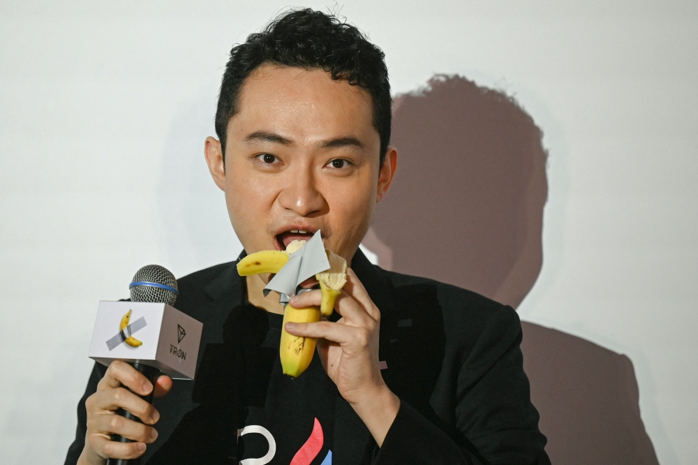 Chinese-born crypto founder Justin Sun eats a banana artwork composed of a fresh banana stuck to a wall with duct tape, in Hong Kong on November 29, 2024, after buying the provocative work of conceptual art by Italian artist Maurizio Cattelan at a New York auction for US$6.2 million (RM27.5 million). — AFP pic