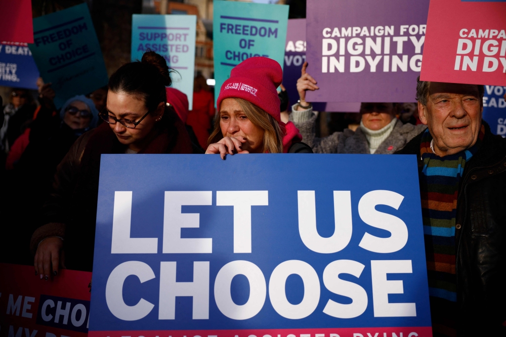 Campaigners supporting the assisted suicide bill hold placards at a demonstration outside The Palace of Westminster in central London, on November 29, 2024, as supporters and opponents of a bill to legalise euthanasia in the UK gather outside the Houses of Parliament while lawmakers debate the bill. — AFP pic