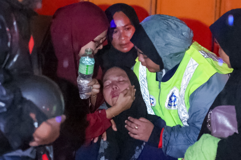 Police officers and family members comfort the mother of the landslide victims in Kampung Bukit Apit, Ajil November 29, 2024. — Bernama pic