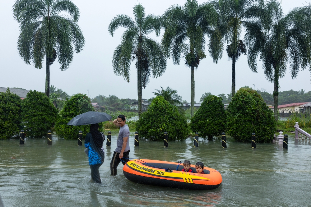 People wade through floodwaters that have begun to recede in Pasir Puteh November 30, 2024. — Bernama pic