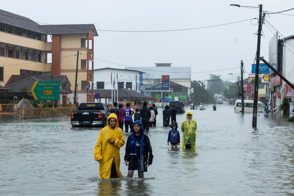 People wade through floodwaters that have begun to recede in Pasir Puteh November 30, 2024. — Bernama pic