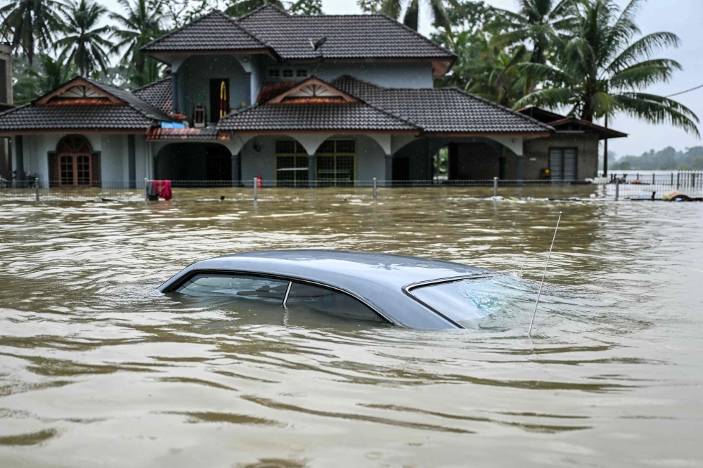 A submerged car is covered by flood waters after days of heavy rain in Tumpat. — AFP pic