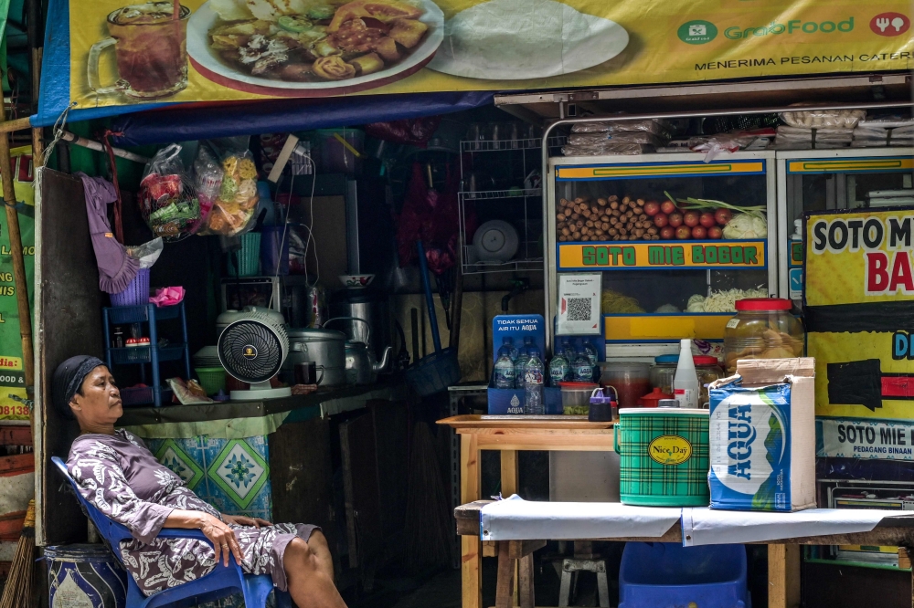 A woman tending a roadside food stall waits for customers during lunchtime in Jakarta, Indonesia on November 29, 2024. — AFP pic