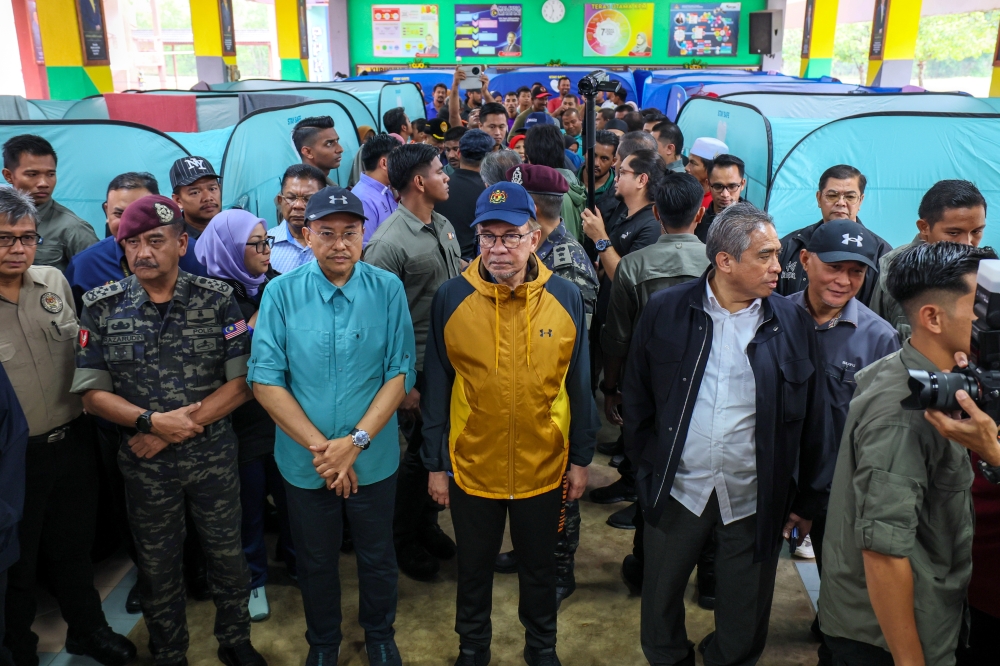 Prime Minister Datuk Seri Anwar Ibrahim listens to a briefing on the latest developments regarding flood victims during his visit to the Temporary Evacuation Centre (PPS) at Telaga Papan National School in Bandar Permaisuri, Terengganu December 1, 2024. — Bernama pic
