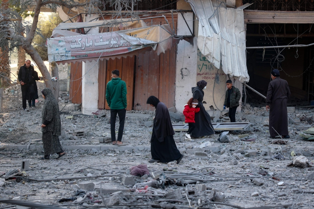 Palestinians walk amid the rubble in front of a building destroyed in an Israeli airstrike in Nuseirat in the central Gaza Strip on December 1, 2024, amid the ongoing war between Israel and Hamas fighters. — AFP pic