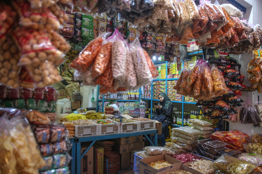 A grocery vendor checks her mobile phone while waiting for customers at Jalan Raja Bot market in Kuala Lumpur October 16, 2024. The word ‘brain rot’ is used to express concern about the consequences of excessive consumption of low-quality online content, especially on social networks. — Picture by Yusof Mat Isa