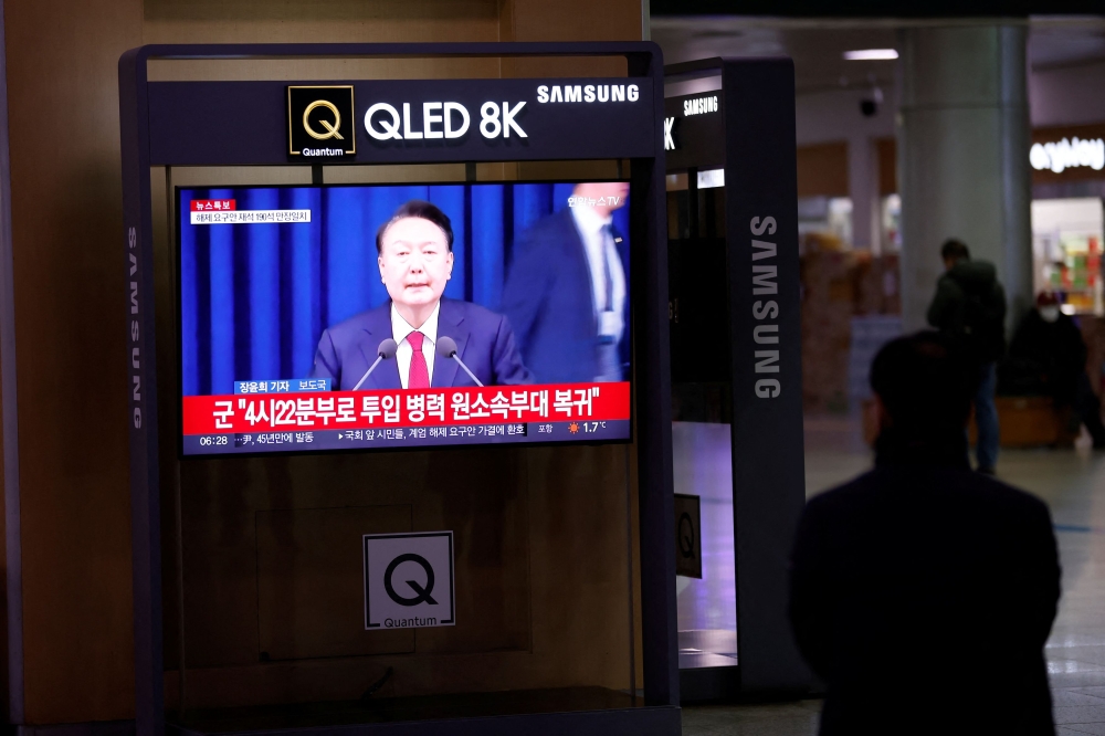 A person watches a TV screen broadcasting a news report on South Korean President Yoon Suk Yeol's declaration of martial law and the following announcement that he will lift the martial law, after parliamentary vote, at a railway station in Seoul, South Korea, December 4, 2024. — Reuters pic