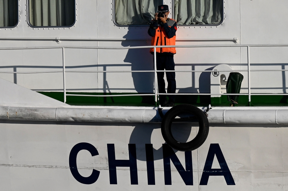 This photo taken on March 5, 2024 shows China Coast Guard personnel filming onboard their vessel in the disputed South China Sea. — AFP pic